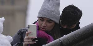A couple take a photo of a snowman in London on Monday December 12.