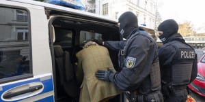 Police arrest a person during raids against so-called “Reich citizens”.
