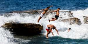 Swimmers leap off Giles Baths in Coogee on Sunday.