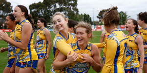 West Coast’s Kate Bartlett (left) and Isabella Lewis celebrate Sunday’s surprise win over Essendon flanked by their teammates.