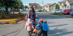 A daycare group walks through a residential neighbourhood in Quebec,where childcare has been unvirsal and provided at a fixed rate per day for more than 25 years.