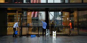 Workers clean the entrance to an office building in Parramatta as people start returning to work in offices.
