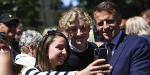 French President Emmanuel Macron poses for pictures outside a polling station during the European election,in northern France.