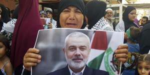 A Hamas supporter holds a poster of its political chief Ismail Haniyeh during a protest to condemn his killing.