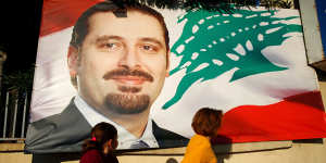 A woman and her daughter pass by a poster of outgoing Prime Minister Saad Hariri,in Beirut,Lebanon.