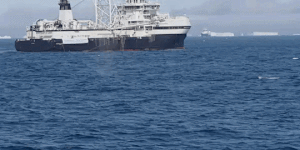 A whale breaches in the Antarctic near a krill trawler.