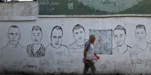 A man walks past paintings of those regarded as martyrs on a wall in Dheisheh refugee camp in Bethhlehem,West Bank.