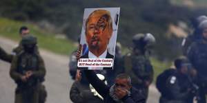 A Palestinian holds up a sign rejecting US President Donald Trump's"peace plan"during protests in the Jordan Valley in February.