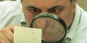 Judge Robert Rosenberg of Broward County Canvassing Board uses a magnifying glass to view a dimpled chad (the bit of paper pushed out when a hole is punched) on a punch-hole ballot in 2000,during a recount of votes in Fort Lauderdale,Florida. 