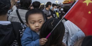 A boy holds a Chinese flag as people gather next to Tiananmen Square on October 1. 