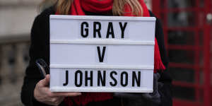 An anti-Boris Johnson protester outside the Houses of Parliament holds a placard referencing the Sue Gray inquiry.