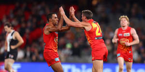 Touk Miller of the Suns (L) congratulates David Swallow of the Suns (C) after he kicked a goal.