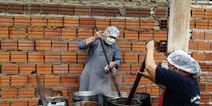 Walter Ferreira,left,and Laura Dure cook stew at a soup kitchen that feeds about 300 people daily in Luque,Paraguay.