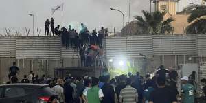 Protesters scale a wall at the Swedish embassy in Baghdad.