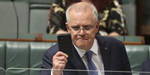Prime Minister Scott Morrison holds up his phone during Question Time.