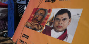 People walk past a poster showing defaced portraits of president Gotabaya Rajapaksa and his brother Basil.