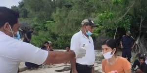 A woman has her temperature checked on the beach in Timor-Leste after arriving by boat.