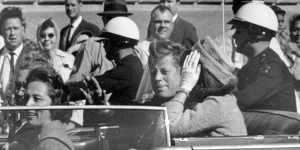 President John F. Kennedy,with wife Jacqueline,waves from his motorcade in Dallas soon before his assassination on November 22,1963. 