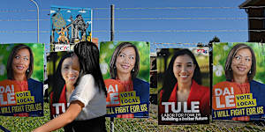 A woman walks past defaced corflutes for independent MP for Fowler Dai Le.