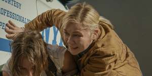 Photographers Jessie (Cailee Spaeney) and Lee (Kirsten Dunst) shelter from attack in a scene from Alex Garland’s Civil War.