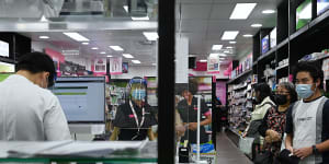 Cabramatta pharmacist Quinn On,at work on the left,worries he will waste his Moderna shots.