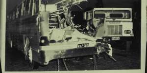 The wrecked tourist coach with the semi-trailer in the background. The impact sheared off the coach's left side. 