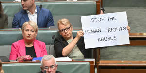 Greens Senator Janet Rice holds a sign as Philippines President Ferdinand Marcos Jr speaks in parliament.