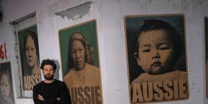 Peter Drew in front of his posters featuring women and children who were born in Australia but had to get exemptions to travel because of the White Australia Policy.