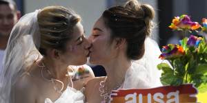 At an event in Bangkok,women kiss while holding a poster to support marriage equality.