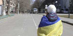 A woman covered by Ukrainian flag stands in front of Russian troops in a street during a rally against Russian occupation in Kherson,Ukraine in March.