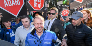 Treasurer Josh Frydenberg voting,surrounded by protesters carrying'Stop Adani'placards.
