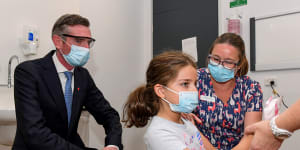 NSW Premier Dominic Perrottet watches on as Ines Panagopailos,8,receives her first dose of the COVID-19 vaccination at the Sydney Children’s Hospital in Randwick on Monday.