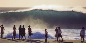 Oahu,Hawaii,January 1999:onlookers and a lone paddler take in the majesty of a fresh swell as it hits the first reef of the infamous Pipeline. The viewing platform is so close that it can feel almost as immersive as being in the water.