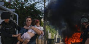 Police officers evacuate a woman and a child from a site hit by a rocket fired from the Gaza Strip,in Ashkelon.