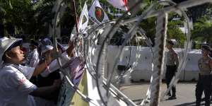 Protesters put up flags and posters on a razor wire barricade as police officers stand guard during a rally alleging a widespread fraud in the presidential election,outside the General Election Commission’s office in Jakarta,Indonesia,on Wednesday.