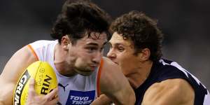 Lachie Ash is tackled by Charlie Curnow during Saturday’s clash. 