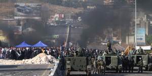 Lebanese army soldiers stand next of their armoured personnel carriers as they prepare to reopen a highway linking Beirut to southern Lebanon blocked by angry protesters,in the coastal town of Jiyeh on Monday.