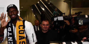 Usain Bolt waves to fans as he walks through Sydney Airport.