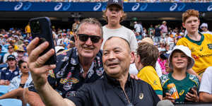 Eddie Jones poses for a selfie with a fan. 