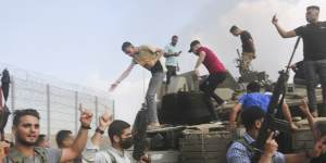 Militants celebrate by an Israeli tank at the border fence of the Gaza Strip on October 7.