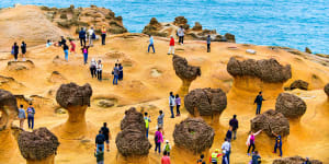 Many tourists walk around the stone shapes at Yehliu Geopark.