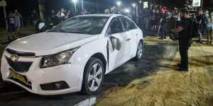 An Israeli police officer inspects the damaged car of an Israeli Arab man who was attacked and injured by an Israeli Jewish mob in Bat Yam,Israel.