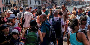 Tourists stand on the Rialto Bridge in Venice. 