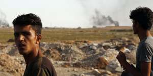 People at the Turkish-Syrian border watch smoke billowing from targets inside Syria during bombardment by Turkish forces.