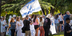 Attendees at the vigil at Hopetoun Gardens in Elsternwick hold an Israeli flag.