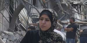 Palestinian women walk by buildings destroyed in Israeli airstrikes in Nuseirat camp in the central Gaza Strip.