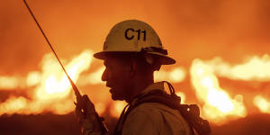 A firefighter communicates in front of the advancing Kenneth Fire in the West Hills section of Los Angeles,Thursday,Jan. 9,2025. (AP Photo/Ethan Swope)