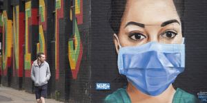 A man walks past mural depicting a nurse wearing a face mask in the Shoreditch area of east London.