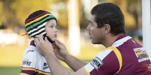 Sean Buchanan adjusts the headgear on his son Beau,who plays for the Glenmore Park Brumbies in the Penrith Junior Rugby League.