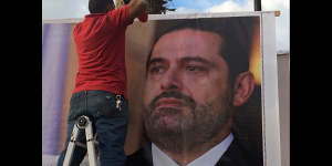 Workers hang a poster of former PM Saad Hariri in Beirut saying:"We are all Saad".